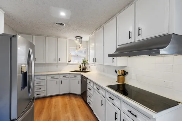 a kitchen with a sink dishwasher a refrigerator and cabinets