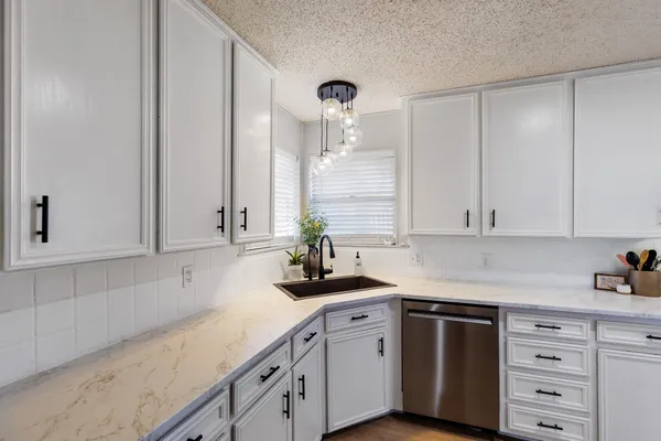 a kitchen with granite countertop white cabinets and white appliances