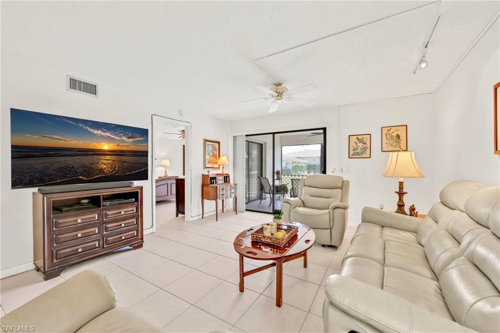 151 Cypress Way East, Unit C103 Naples, FL 34110 - Photo 12 of 29 a living room with furniture and a flat screen tv