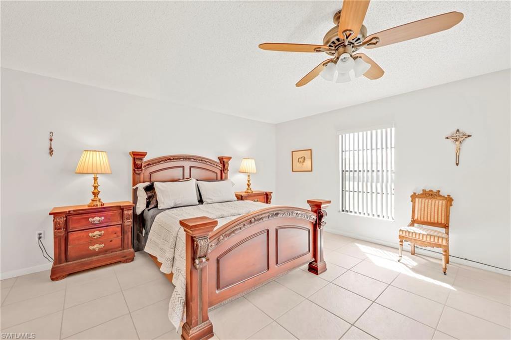 151 Cypress Way East, Unit C103 Naples, FL 34110 - Photo 15 of 29 a bedroom with a bed and a chandelier