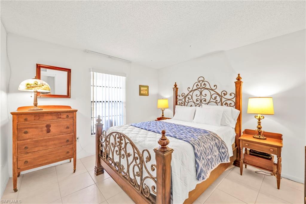 151 Cypress Way East, Unit C103 Naples, FL 34110 - Photo 19 of 29 a bedroom with a bed and a table in it