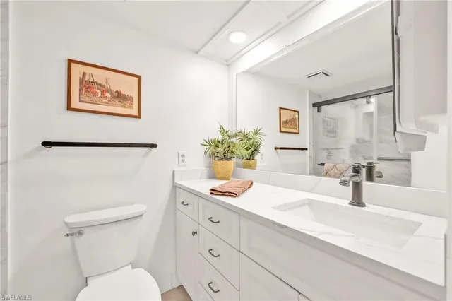a bathroom with a granite countertop sink mirror vanity and toilet
