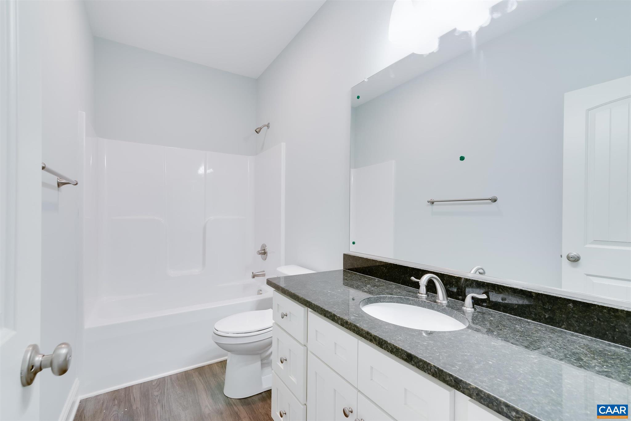 6008 Old Columbia Road Columbia, VA 23038 - Photo 19 of 23 a bathroom with a granite countertop sink toilet a large mirror a bathtub and shower