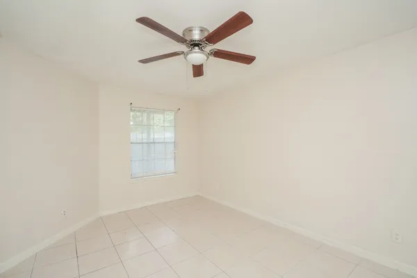 an empty room with a window and a fan