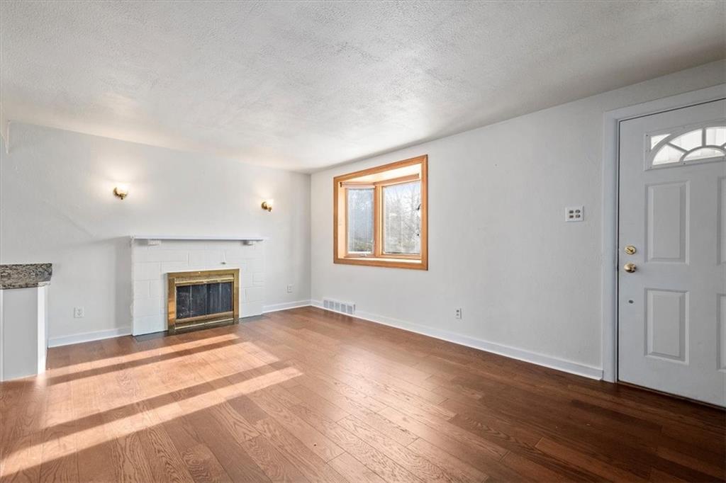 504 Nichols Road Pittsburgh, PA 15237 - Photo 3 of 25 an empty room with wooden floor fireplace and windows