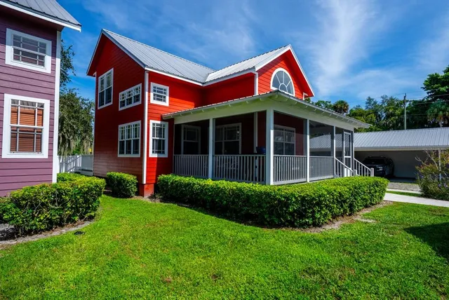 a view of a brick house with a yard large tree and a large window