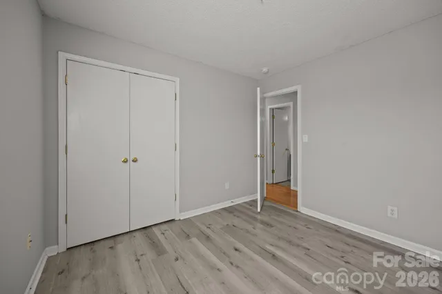 a view of an empty room with wooden floor and closet