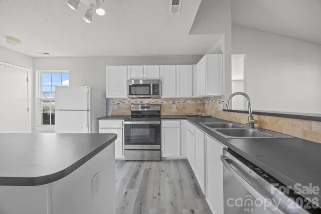 a kitchen with kitchen island a sink appliances cabinets and a counter top space
