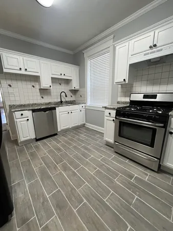 a kitchen with stainless steel appliances a stove a sink and white cabinets