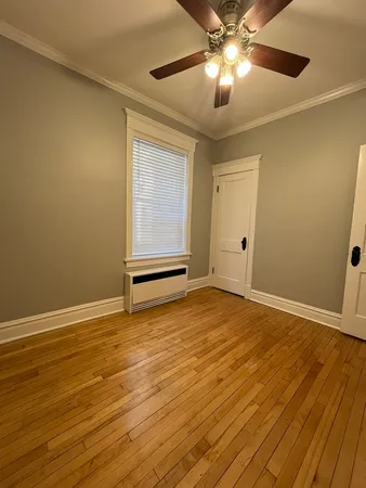 a view of an empty room with wooden floor and a ceiling fan