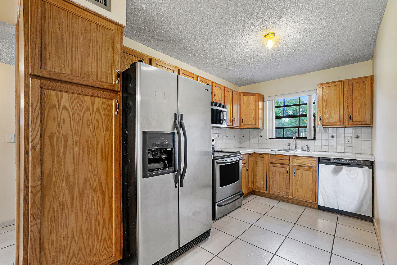3050 Norwood Place, Unit N112 Boca Raton, FL 33431 - Photo 7 of 23 a kitchen with stainless steel appliances granite countertop a refrigerator and a stove top oven