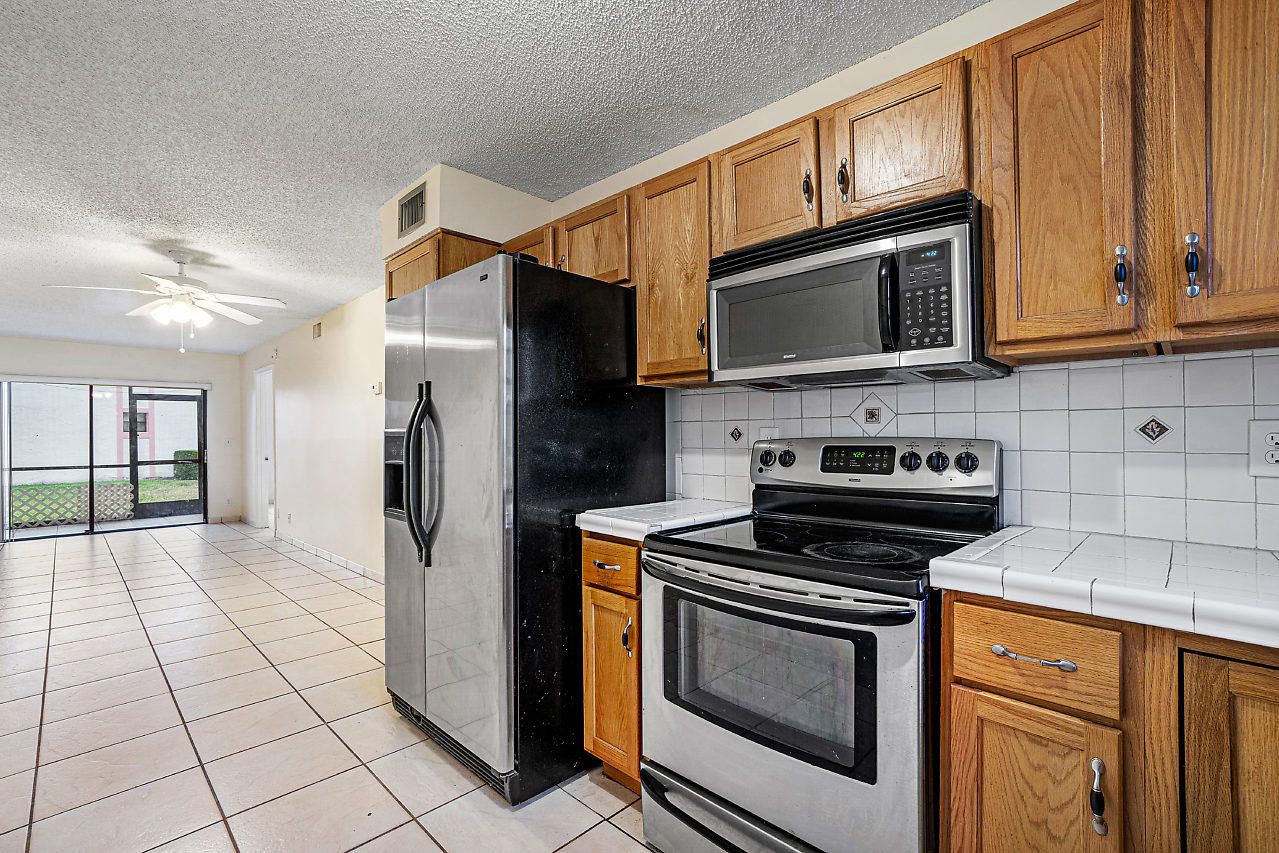 3050 Norwood Place, Unit N112 Boca Raton, FL 33431 - Photo 8 of 23 a kitchen with granite countertop a stove microwave and refrigerator