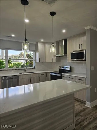a large kitchen with stainless steel appliances granite countertop a stove and a wooden floor