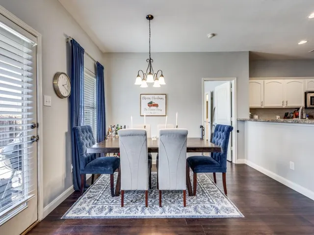 a dining room with wooden floor a chandelier a wooden table and chairs