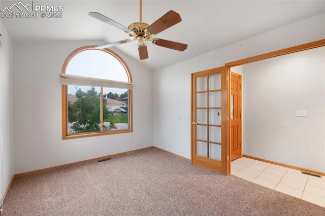 an empty room with windows and fan