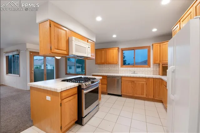 a kitchen with stainless steel appliances granite countertop a stove a sink and a refrigerator