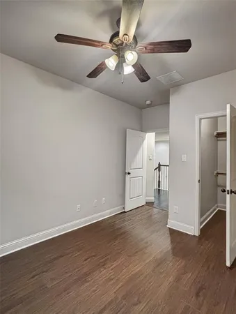a view of an empty room with wooden floor and a ceiling fan