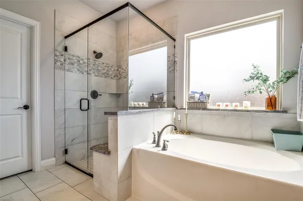 a bathroom with a tub a mirror and a shower