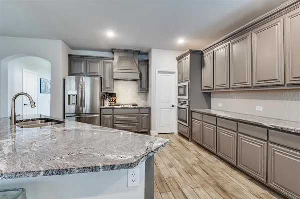 a kitchen with stainless steel appliances granite countertop a sink a stove and a refrigerator