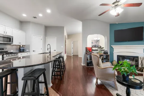 a kitchen with stainless steel appliances granite countertop a stove a sink a microwave a refrigerator and white cabinets