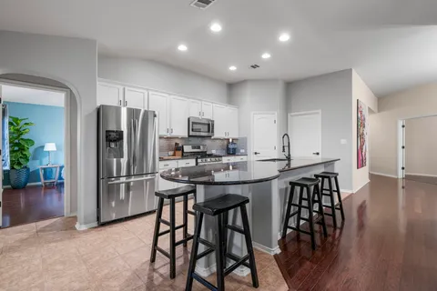 a kitchen with kitchen island granite countertop a table chairs microwave and refrigerator