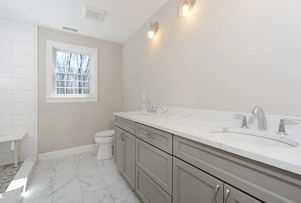 a bathroom with a granite countertop sink a toilet and a window