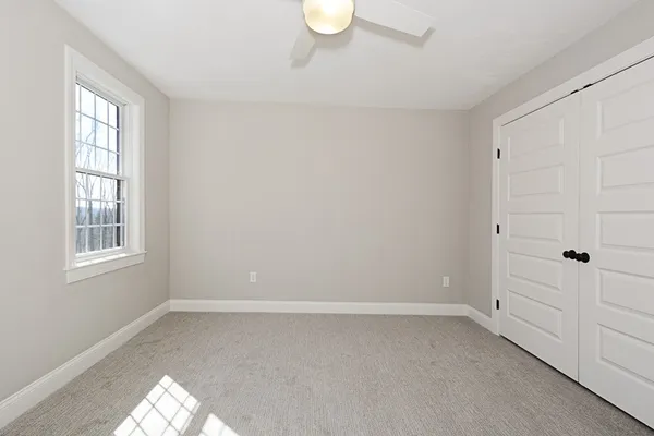 a view of an empty room with a window and closet area
