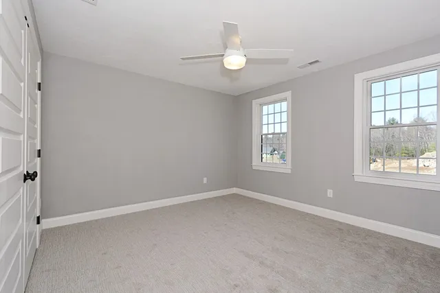 an empty room with windows and fan