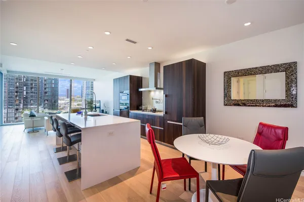 a living room with stainless steel appliances a dining table wooden floor and a view of kitchen