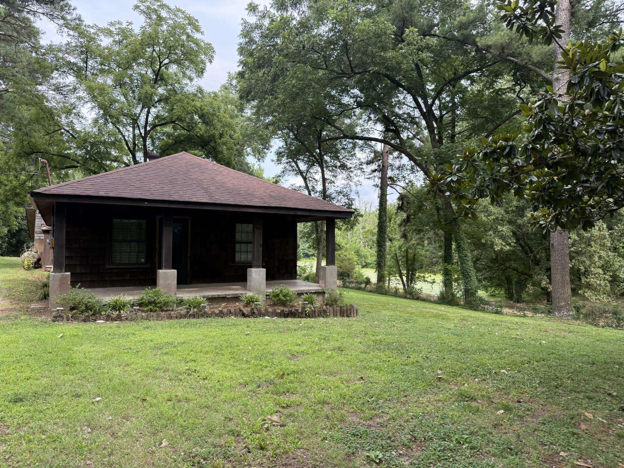 6760 Locke Road Millington, TN 38053 - Photo 31 of 39 Charming cabin with a covered front porch featuring concrete pillars, a gabled roof, and wood-paneled siding