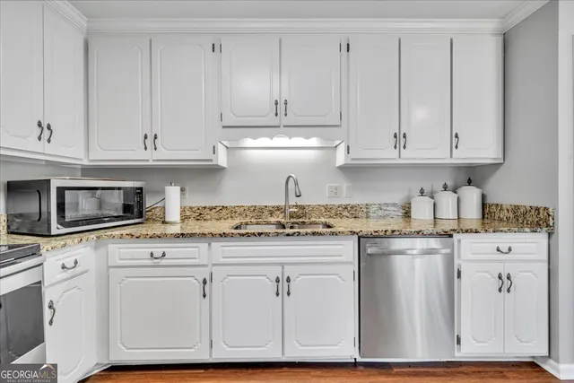 a kitchen with granite countertop white cabinets and a stainless steel appliances