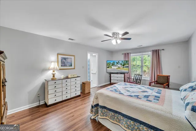 a bedroom with a bed and a dresser with wooden floor