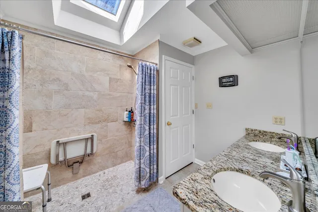 a bathroom with a granite countertop sink a mirror and shower