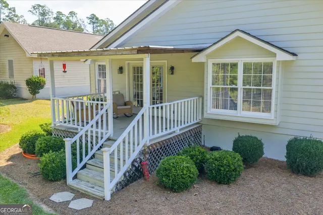 a view of a house with a yard plants and large tree