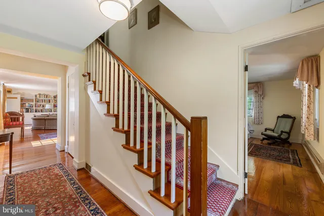 a view of a hallway to a livingroom with wooden floor and furniture