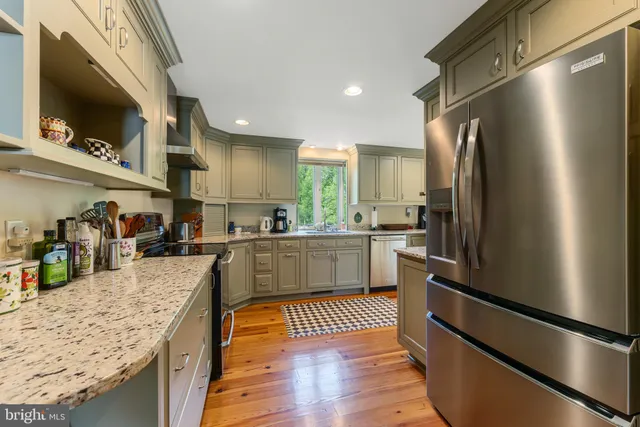 a kitchen with stainless steel appliances granite countertop a refrigerator a sink and a stove