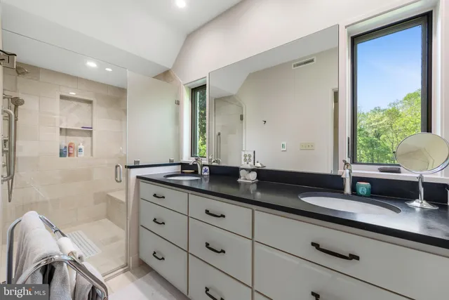 a bathroom with a granite countertop double vanity sink a mirror and a bathtub