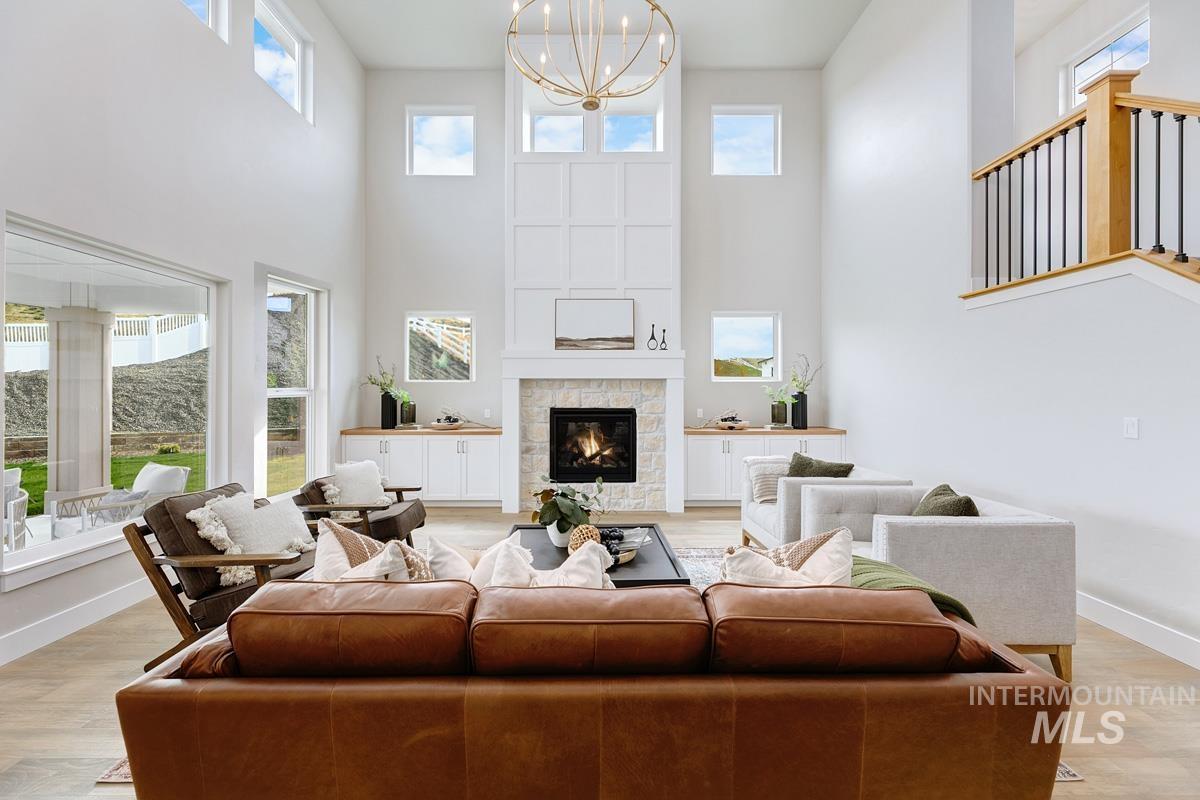 13544 North Ruffed Grouse Place Boise, ID 83714 - Photo 2 of 42 Living room featuring light wood-type flooring, suspended lighting, plenty of natural light, a tiled fireplace, and a high ceiling