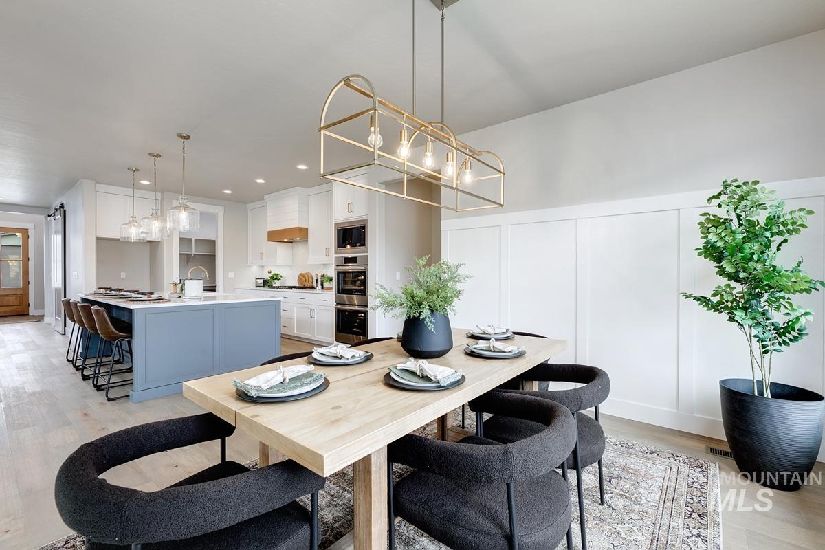 13544 North Ruffed Grouse Place Boise, ID 83714 - Photo 6 of 42 Dining room with light wood-type flooring, a chandelier, and a decorative wall