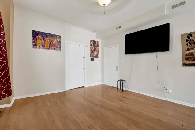 a view of an empty room with wooden floor and a flat screen tv