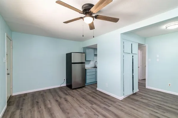 a view of empty room with wooden floor and ceiling fan
