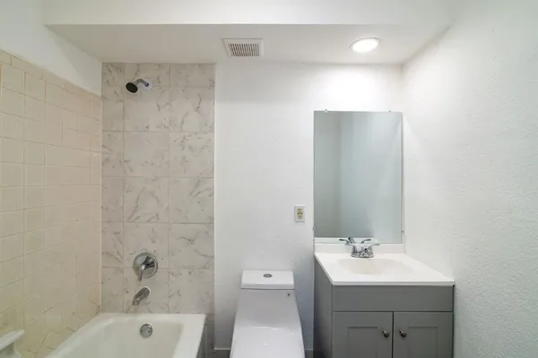 a bathroom with a toilet a sink a mirror and shower