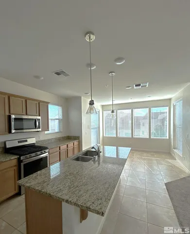 a large kitchen with kitchen island a large counter top space a sink stainless steel appliances and cabinets