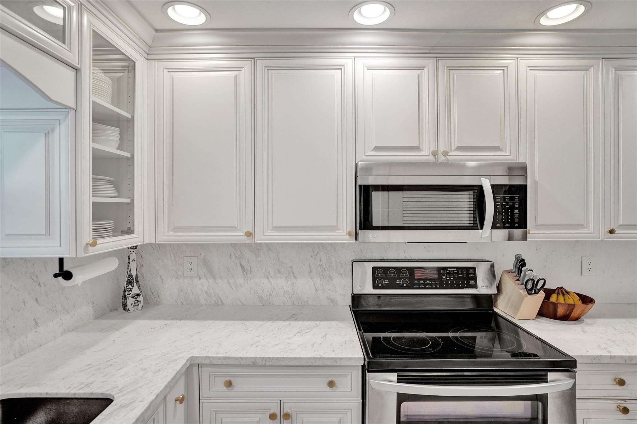 2501 South Ocean Boulevard, Unit 103 Boca Raton, FL 33432 - Photo 11 of 49 a kitchen with stainless steel appliances white cabinets and a stove top oven