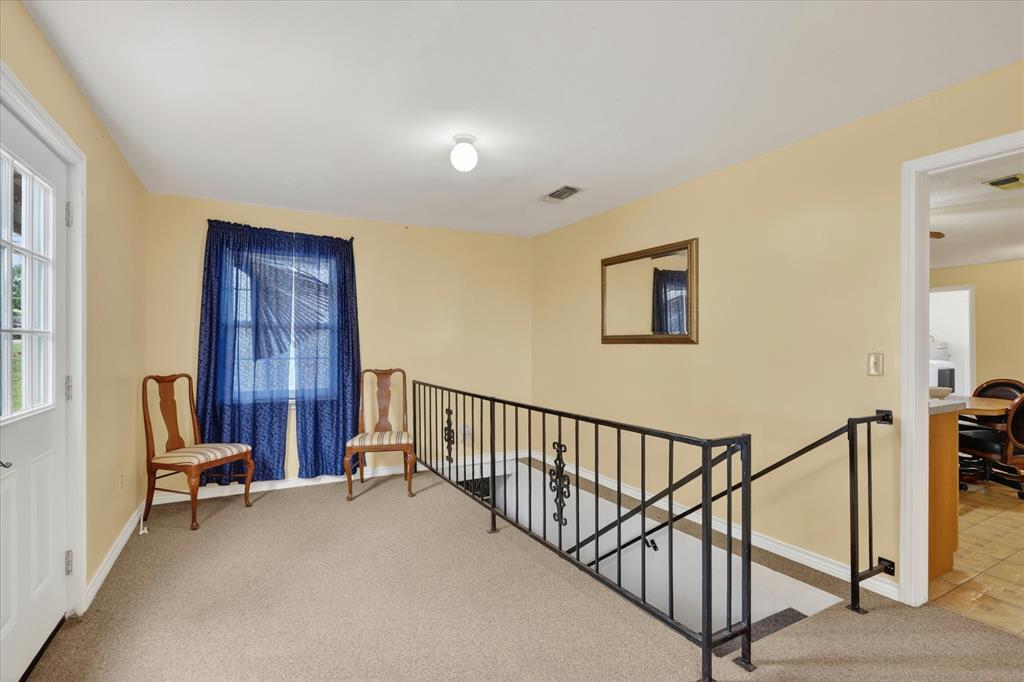 1092 West Highway 199 Springtown, TX 76082 - Photo 6 of 29 Carpeted landing featuring a white paneled door with glass inserts, a window, and black metal stair railings leading to basement.