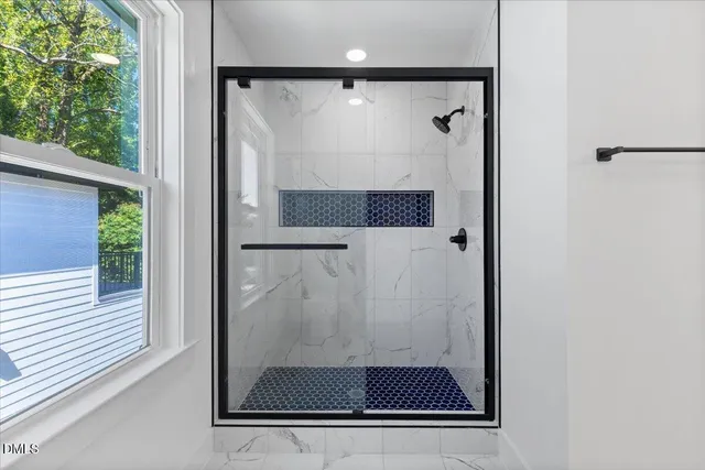 a bathroom with a glass shower door and a window