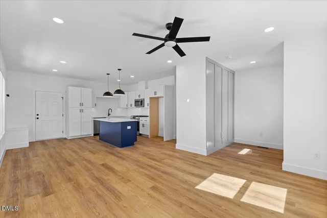 a kitchen with kitchen island white cabinets and a chandelier fan