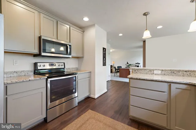 a kitchen with stainless steel appliances granite countertop a stove a sink and a microwave