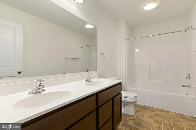 a bathroom with a sink double vanity granite tub shower and a mirror