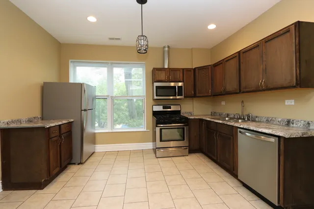 a kitchen with stainless steel appliances granite countertop a refrigerator and a stove top oven